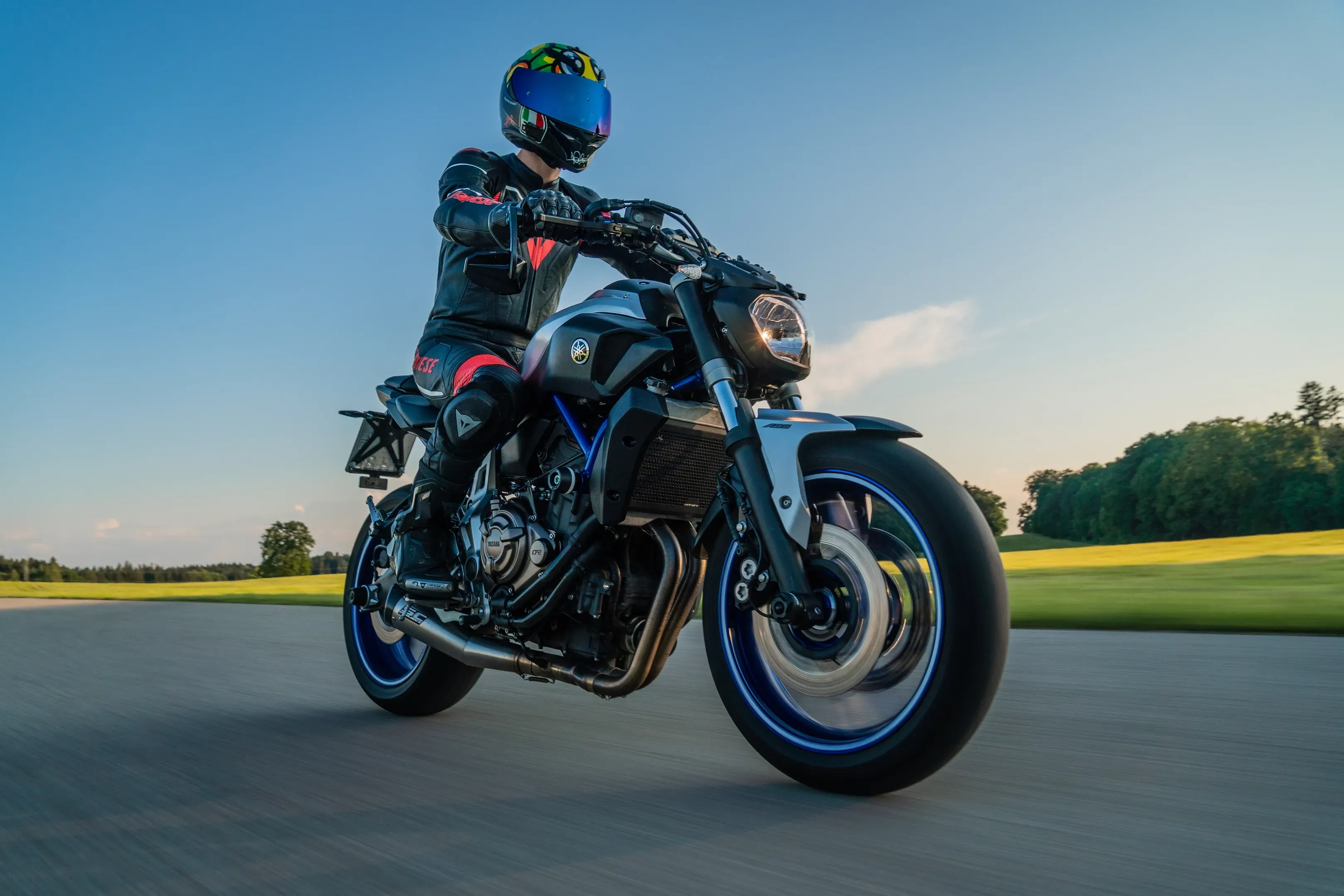 Fahrer in Lederkombi auf einer Yamaha Naked Bike, aus tiefer Perspektive auf einer Straße bei blauem Himmel