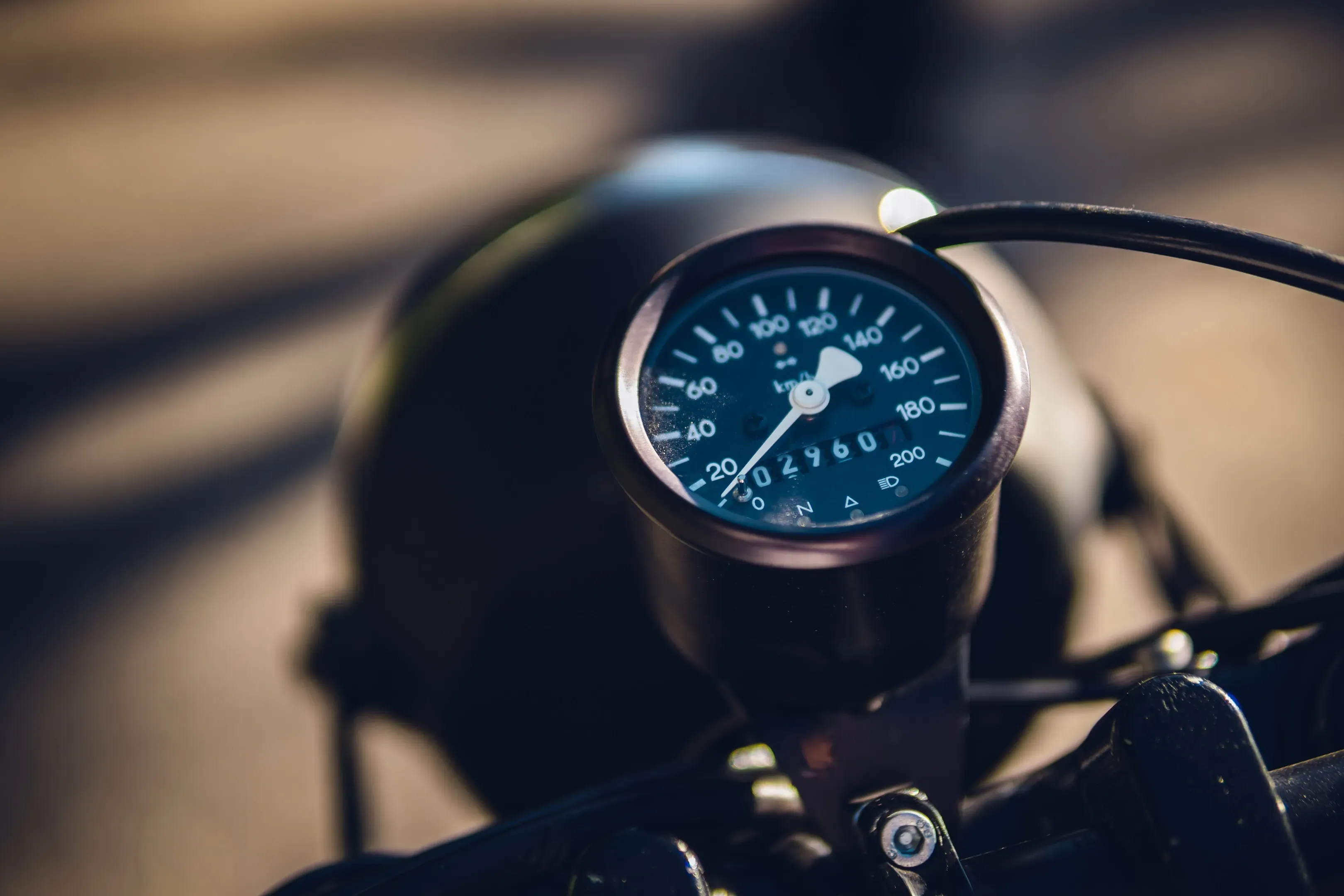 Runder Tachometer eines Motorrads mit Kilometerzähler, im warmen Licht vor unscharfem Hintergrund