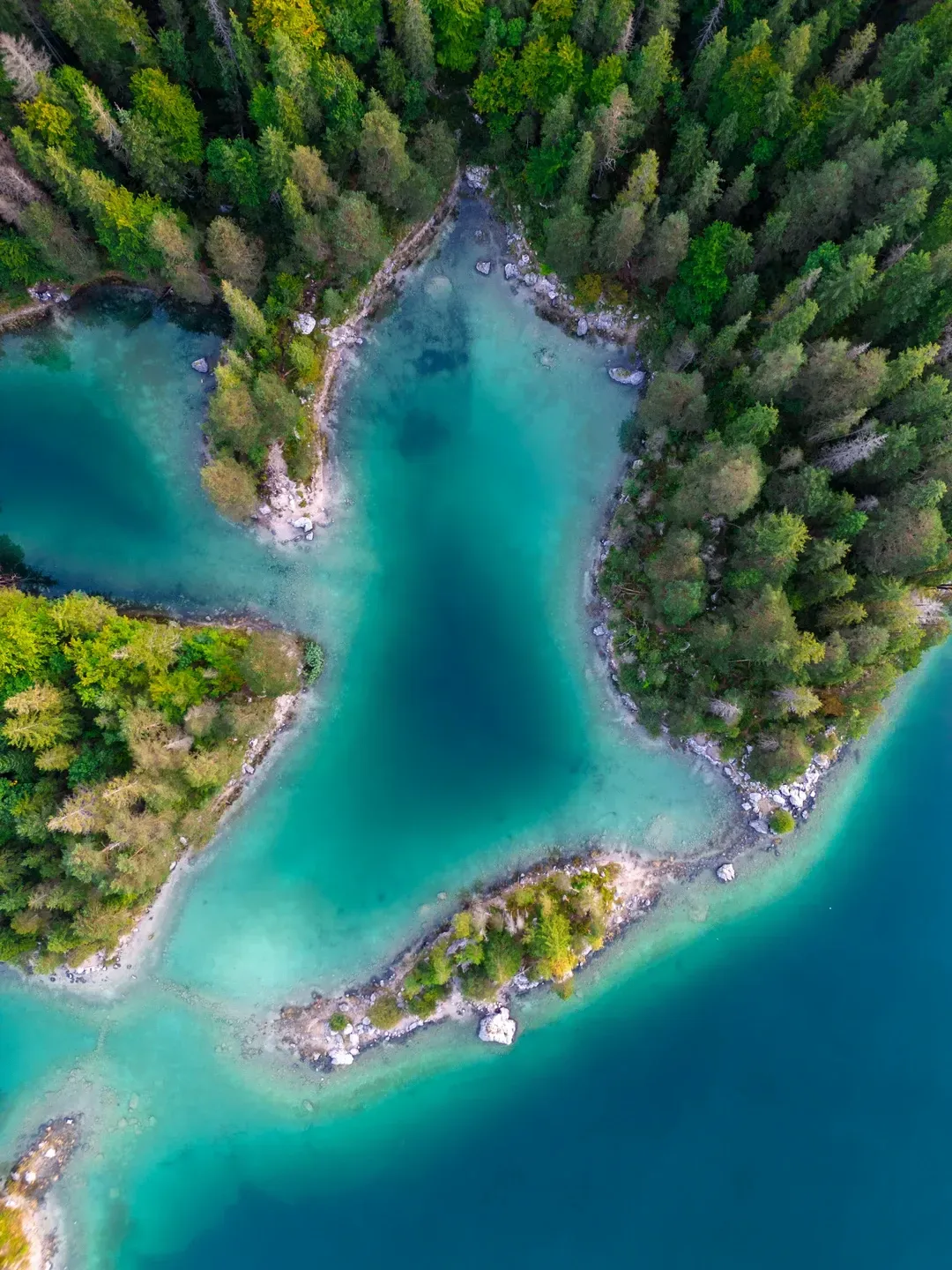 Luftaufnahme einer Seebucht mit türkisem Wasser, bewaldeten Landzungen und kleinen Inseln